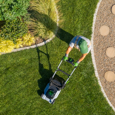 Aerial view of gardener mowing a backyard lawn